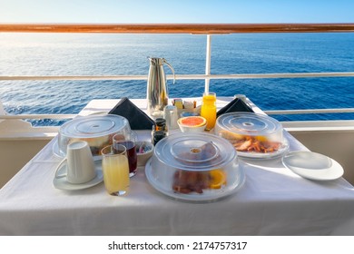 A Full Room Service Breakfast On A Balcony Of A Cruise Ship Cabin At Sea Including Juice, Coffee And Full Meals On A Sunny Luxury Vacation On The Sea.