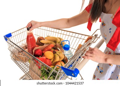 Full shopping cart at store with fresh vegetables and hands close-up.