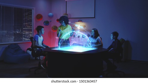 Full Shot Of A Female Teacher Using A Planet Earth Hologram While Explaining To Student In Class