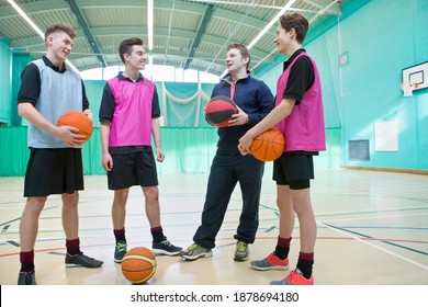 Full Shot Of A Gym Teacher Teaching Basketball To A Group Of High School Students In A Gym.