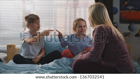 Full shot of a mother trying to reconcile bickering siblings
