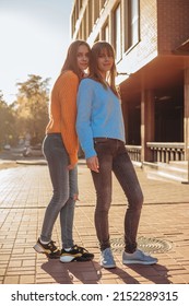 Full Shot Portrait In Low Camera Angle Of Female Twins In The Same Clothes.