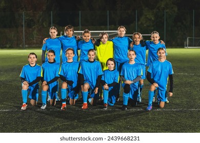 full shot of teenage football player girls in blue uniforms taking a group photo before match. High quality photo - Powered by Shutterstock