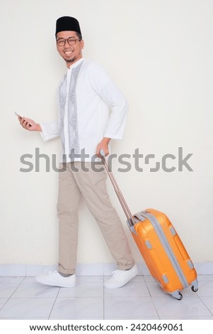 Full side body portrait of Moslem man walking with suitcase and mobile phone
