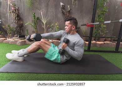 Full Situps With Dumbbells And Alternate Cross Punch. Performed By A Fit Asian Guy Lying On A Black Mat. Intense Reciprocal Exercise At A Home Gym. SIde View.