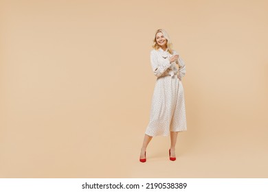 Full size body length blithesome delight ecstatic fun elderly gray-haired blonde woman lady 40s years old wears pink dress looking down posing isolated on plain pastel beige background studio portrait