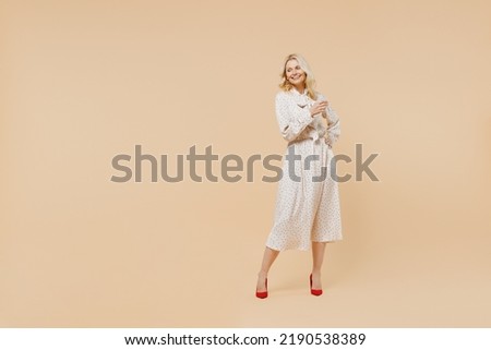 Full size body length blithesome delight ecstatic fun elderly gray-haired blonde woman lady 40s years old wears pink dress looking down posing isolated on plain pastel beige background studio portrait