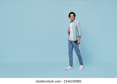 Full Size Body Length Charismatic Blithesome Young Black Curly Man 20s Years Old Wears White Shirt Stepping Walking Strolling Move Pace Isolated On Plain Pastel Light Blue Background Studio Portrait