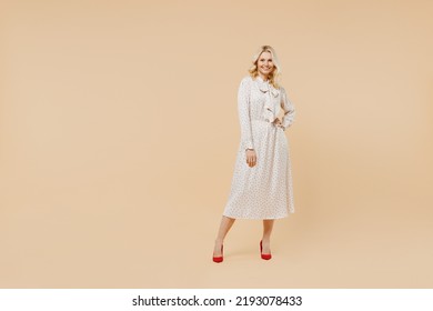 Full size body length charming elderly gray-haired blonde woman lady 40s years old wears pink dress hold hand on waist looking camera posing isolated on plain pastel beige background studio portrait - Powered by Shutterstock