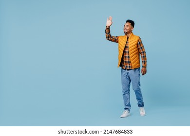 Full Size Body Length Fancy Charming Young Black Man 20s Years Old Wears Yellow Waistcoat Shirt Greet Meet Waving Hand As Notices Someone Isolated On Plain Pastel Light Blue Background Studio Portrait