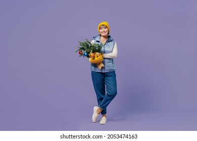 Full Size Body Length Happy Mature Elderly Senior Lady Woman 55 Years Old Wears Blue Waistcoat Yellow Hat Mittens Holds Spruce Branches Isolated On Plain Pastel Light Violet Background Studio Portrait