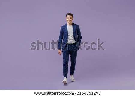 Full size body length happy young successful employee business man lawyer 20s wear formal blue suit white t-shirt work in office move hand in pocket isolated pastel purple background studio portrait