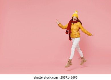 Full Size Body Length Jubilant Young Woman 20s Years Old Wear Yellow Jacket Hat Mittens Look Camera Jump Move Go Keep Mouth Open Hurry Up Isolated On Plain Pastel Light Pink Background Studio Portrait