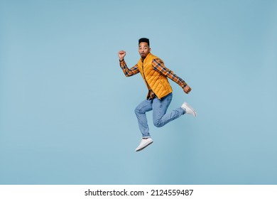 Full Size Body Length Side Profile View Amazed Surprised Young Black Man 20s Years Old Wears Yellow Waistcoat Shirt Jump Clenching Fists Isolated On Plain Pastel Light Blue Background Studio Portrait