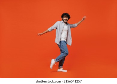 Full Size Body Length Side Profile View Jubilant Young Bearded Indian Man 20s Years Old Wears Blue Shirt Dance Waving Fooling Around Have Fun Enjoy Isolated On Plain Orange Background Studio Portrait