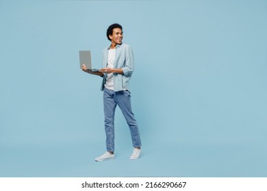 Full Size Body Length Side View Profile Fun Young Black Curly Man 20s Wears White Shirt Hold Use Work On Laptop Pc Computer Looking Back Isolated On Plain Pastel Light Blue Background Studio Portrait