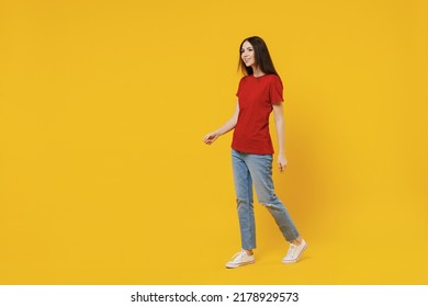 Full Size Body Length Side View Profile Excited Young Brunette Woman 20s Wears Basic Red T-shirt Walk Go Move Stroll Isolated On Yellow Background Studio Portrait. People Emotions Lifestyle Concept