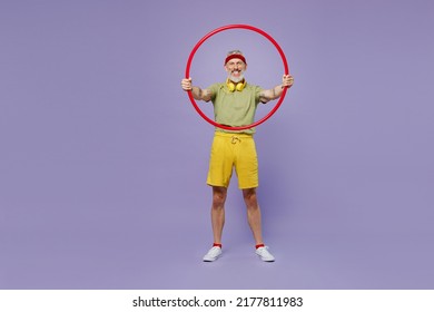 Full Size Body Length Sporty Fun Elderly Gray-haired Bearded Man 60s Years Old In Headband Khaki T-shirt Hold Look Through Sports Hoop Isolated On Plain Pastel Light Purple Background Studio Portrait