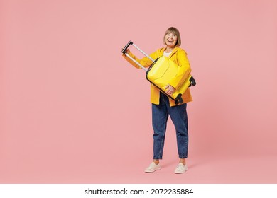 Full Size Body Length Traveler Tourist Mature Elderly Woman 55 Years Old Wear Casual Clothes Hat Scarf Hold Carry Suitcase Bag Under Hand Isolated On Plain Pastel Light Pink Background Studio Portrait