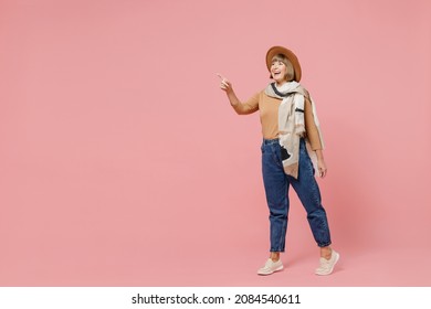 Full Size Body Length Traveler Tourist Mature Elderly Senior Lady Woman 55 Years Old Wears Brown Shirt Hat Scarf Point Insex Finger Aside Isolated On Plain Pastel Light Pink Background Studio Portrait