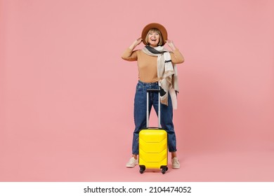 Full Size Body Length Traveler Tourist Joyful Mature Elderly Senior Woman 55 Years Old Wears Casual Clothes Hat Scarf Hold Suitcase Bag Isolated On Plain Pastel Light Pink Background Studio Portrait