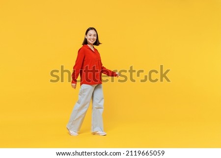 Full size body length vivid young woman of Asian ethnicity 20s years old in casual clothes look camera go move isolated on plain yellow background studio portrait. People emotions lifestyle concept