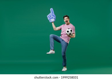 Full Size Body Length Young Fun Man Fan Wear Basic Pink T-shirt Cheer Up Support Football Sport Team Hold In Hand Soccer Ball Watch Tv Live Stream Scream Isolated On Dark Green Color Background Studio