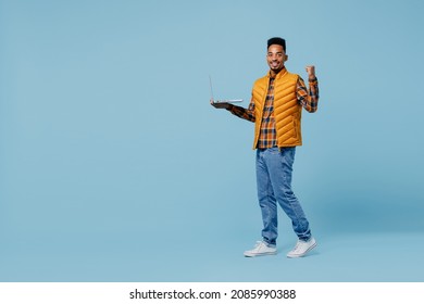 Full Size Body Length Young Black Man 20s Years Old Wears Yellow Waistcoat Shirt Hold Use Work On Laptop Pc Computer Doing Winner Gesture Isolated On Plain Pastel Light Blue Background Studio Portrait