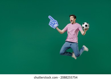 Full Size Body Length Young Fun Man Fan Wear Pink T-shirt Cheer Up Support Football Sport Team Hold In Hand Soccer Ball Watch Tv Live Stream Scream Jump Isolated On Dark Green Color Background Studio