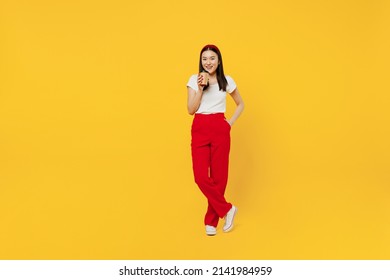 Full size body length young girl woman of Asian ethnicity 20s years old in casual clothes hold takeaway delivery craft paper brown cup coffee to go isolated on plain yellow background studio portrait