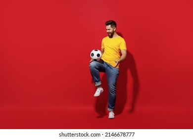 Full Size Body Length Young Bearded Man Football Fan In Yellow T-shirt Cheer Up Support Favorite Team Juggling Soccer Ball Isolated On Plain Dark Red Background Studio Portrait. Sport Leisure Concept