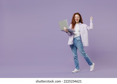 Full size body length young redhead curly woman 20s wears white T-shirt violet jacket hold use work on laptop pc computer do winner gesture isolated pastel purple color wall background studio portrait - Powered by Shutterstock