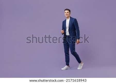 Full size body length young successful employee business man lawyer 20s wear formal blue suit white t-shirt work in office move stroll look aside isolated on pastel purple background studio portrait