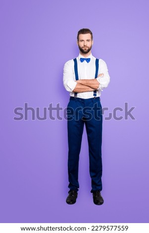 Full size full body portrait of famous talented singer in blue ourfit, wearing bow, white shirt, suspenders, isolated over grey background, holding arms crossed
