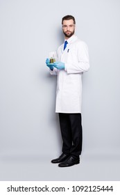 Full Size Fullbody Portrait Of Attractive Stylish Scientist In White Lab Coat, Black Pants, Shoes, Tie Holding Test Tubes With Multi-colored Liquid, Looking At Camera, Isolated On Grey Background