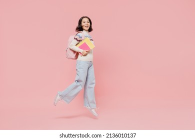 Full Size Happy Excited Teen Student Girl Of Asian Ethnicity Wear Sweater Hold Backpack Books Jump High Look Camera Isolated On Pastel Plain Pink Background Education In University College Concept.