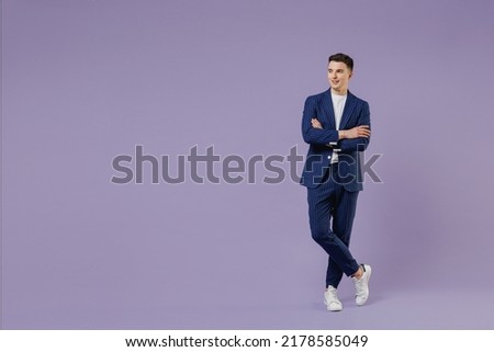 Full size happy young successful employee business man lawyer 20s wear formal blue suit white t-shirt work in office hold hands crossed look aside isolated on pastel purple background studio portrait