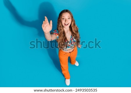 Full size high angle view photo of nice young girl arm wave wear top isolated on blue color background