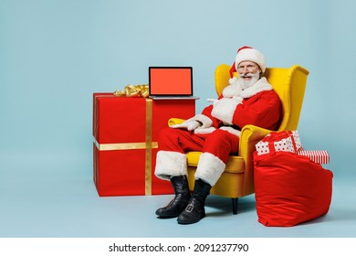 Full size old Santa Claus man in Christmas hat red suit clothes sit in chair use laptop pc computer blank screen isolated on plain blue background studio Happy New Year merry ho x-mas holiday concept - Powered by Shutterstock