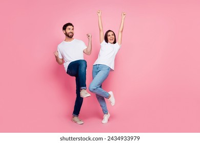 Full size photo of attractive young couple raise fists look empty space wear trendy white clothes isolated on pink color background - Powered by Shutterstock