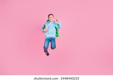 Full size photo of beautiful delighted boy jump hold book bag raise fist empty space isolated on pink color background - Powered by Shutterstock