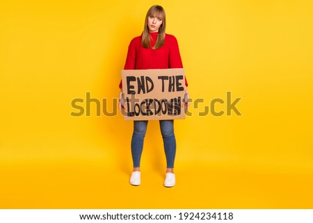 Full size photo of blond sad lady stand with poster wear red sweater jeans sneakers isolated on bright yellow color background