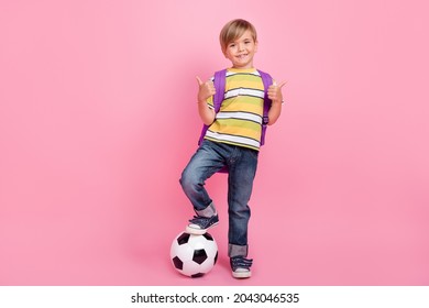 Full size photo of blonde little boy wear bag hands show thumb up game football isolated on pink color background