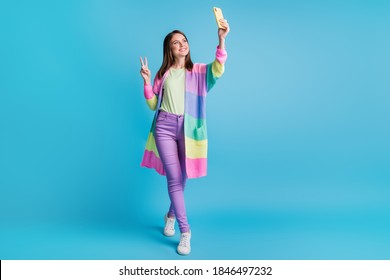 Full Size Photo Of Brown Haired Blogger Girl Make V-sign Take Selfie Record Video Hold Phone Wear Purple Pants Isolated On Blue Color Background