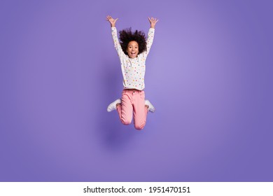 Full Size Photo Of Brown Haired Small Excited Dark Skin Girl Jump Up Raise Hands Wear White Pullover Isolated On Violet Color Background