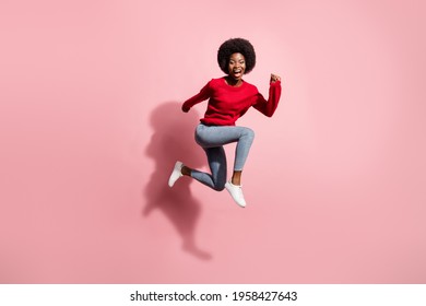 Full size photo of brunette pretty afro american lady jump up run empty space excited isolated on pink color background