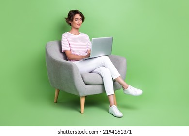 Full size photo of charming young woman focused laptop confident manager wear stylish striped garment isolated on green color background - Powered by Shutterstock