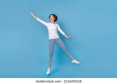 Full size photo of cheerful excited energetic girl hold parasol during autumn rains fooling around isolated on blue color background - Shutterstock ID 2116350518