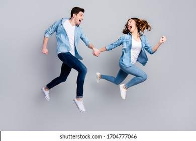 Full size photo of cheerful funky students spouses enjoy spring weekend rest jump hold hand run moving wear casual style outfit gumshoes isolated over gray color background - Powered by Shutterstock