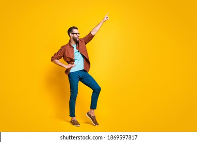 Full size photo of cheerful happy handsome young guy dance point finger hold hand waist empty space isolated on yellow color background - Shutterstock ID 1869597817